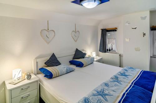 a bedroom with a white bed with blue pillows at Ferienhaus Grietjes Huus in Krummhörn