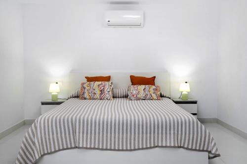a white bedroom with a large bed with two lamps at Brisa 3 in La Santa
