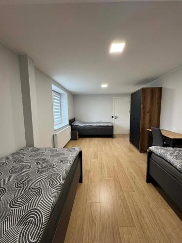 a bedroom with two beds and a desk in it at kambariu nuoma in Dovilai