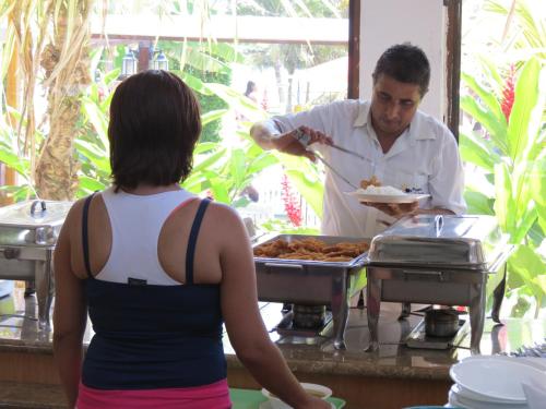 a man serving a woman a plate of food at Hotel Puerto Ballesta in Tonsupa