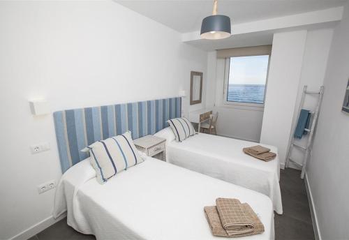 two beds in a room with the ocean in the background at Super Front Line Modern New Apartm in Nerja