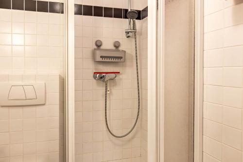 a shower in a white tiled bathroom at Ferienwohnung Fetscher 2 in Reichenau