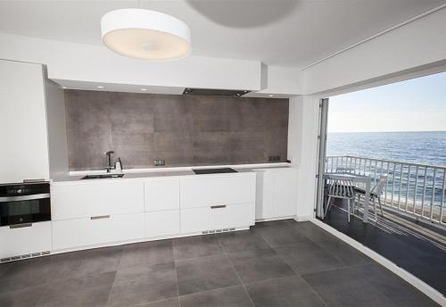 a kitchen with white cabinets and a view of the ocean at Super Front Line Modern New Apartm in Nerja