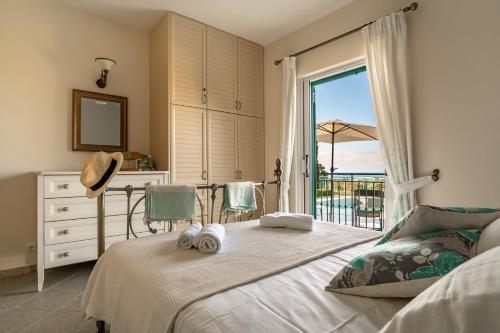 a bedroom with a bed and a balcony with the ocean at Villa Millianna Exclusive Apartment in Kefallonia