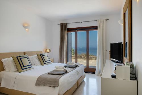 a bedroom with a bed with a view of the ocean at Blueros - Sand Suite in Megas Gialos - Nites