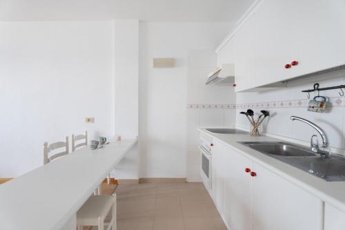 a white kitchen with white cabinets and a sink at Bajamar - Apart-Piscina naturales in Bajamar