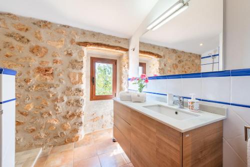 a bathroom with a sink and a stone wall at Els Garroverets in Binissalem
