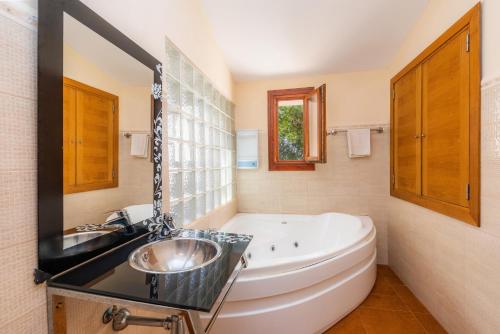 a bathroom with a large tub and a sink at Ses Angoixes in Santanyi