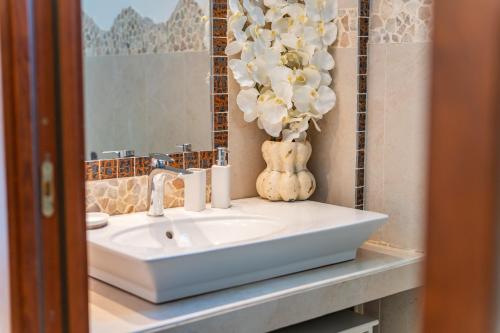 a bathroom with a sink and a vase of flowers at Villa Alice in Villasimius