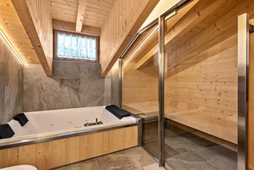 a bath tub in a bathroom with wooden walls at Luxury Apartment Majon de Rita in Vigo di Fassa