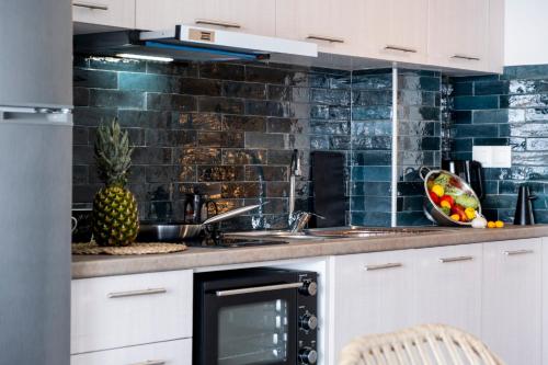 a kitchen with white cabinets and a black tile wall at Oceanida Afrodite Lyxury Suite in Nikiana