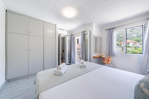 a white bedroom with a large white bed and a window at Casa Di Babis in Gaios