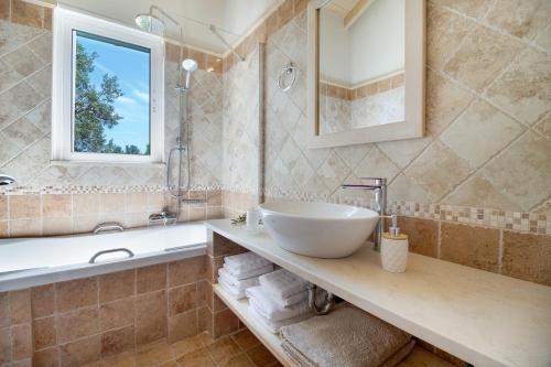 a bathroom with a sink and a tub and a mirror at Villa Belvedere Verde in Lefkada