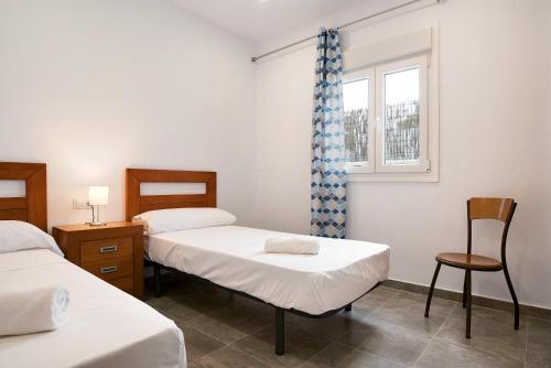 a room with two beds and a chair and a window at Villa Montenmedio - Juande in El Soto