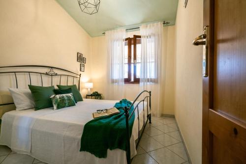 a bedroom with a bed with a green blanket on it at Chelubirdi in Villasimius