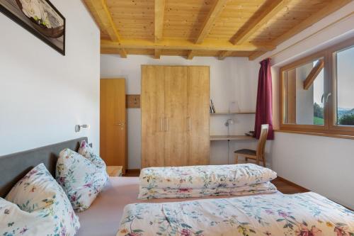 a bedroom with two beds and a window and a kitchen at Kohlerhof Apartment in San Genesio Atesino