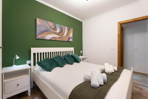 a bedroom with a white bed with green walls at Los Almendr2s in Frontera