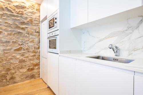 a white kitchen with a sink and a stone wall at Casa del Campanar in Traiguera