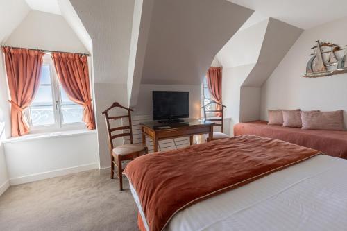 a bedroom with a bed and a desk with a television at Hôtel de la Pointe du Grouin in Cancale