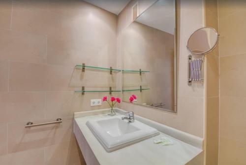a white bathroom with a sink and a mirror at Es Port penthouse in Santanyi