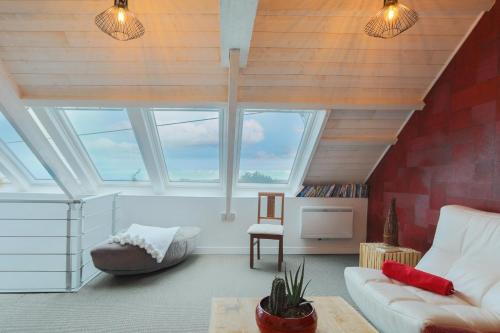 a living room with windows and a couch and a table at Le clos du Verdelet vue mer piscine in Planguenoual