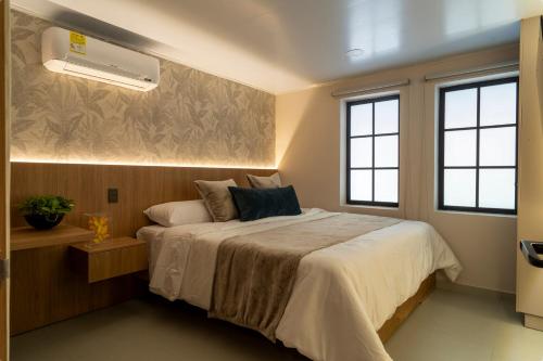 a bedroom with a bed in a room with windows at Bruma Verde Casa Hotel in Medellín