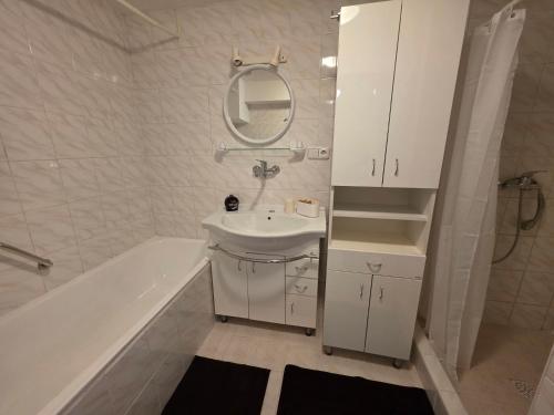 a bathroom with a sink and a tub and a mirror at Vila Daniela in Luhačovice