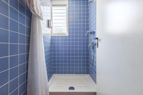 a blue tiled bathroom with a shower with a window at Masia Alt in Olerdola