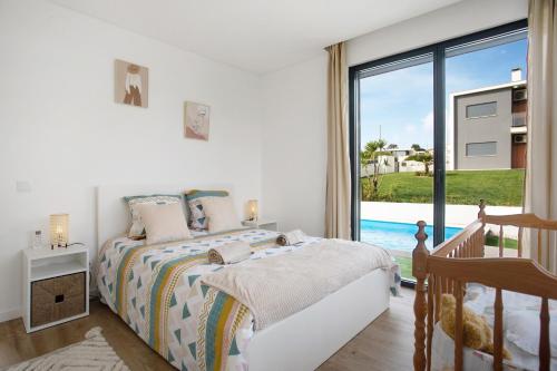 a white bedroom with a bed and a large window at Villa Atlantic View in Salir de Porto