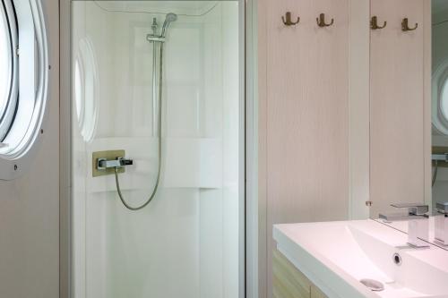 a white bathroom with a shower and a sink at Mobil-home in Angles