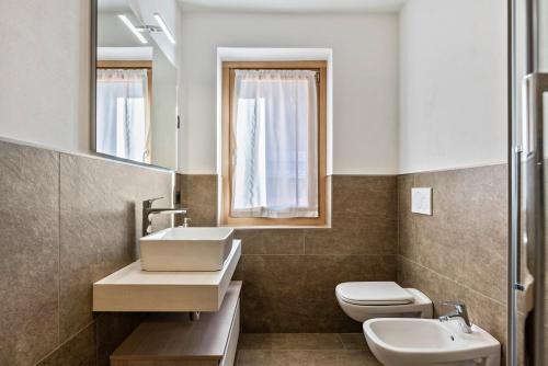 a bathroom with a sink and a toilet and a mirror at Condominio Lucia 7 Pinzolo in Pinzolo