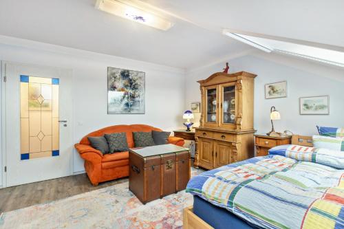 a bedroom with a bed and an orange chair at Ferienwohnung Zur Henne in Weinbach