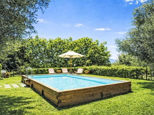 a swimming pool with an umbrella and two chairs at Apartment Cotoneaster by Interhome in Perugia