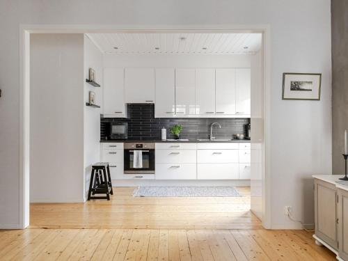 a kitchen with white cabinets and a wooden floor at Apartment Alegränd by Interhome in Falkenberg