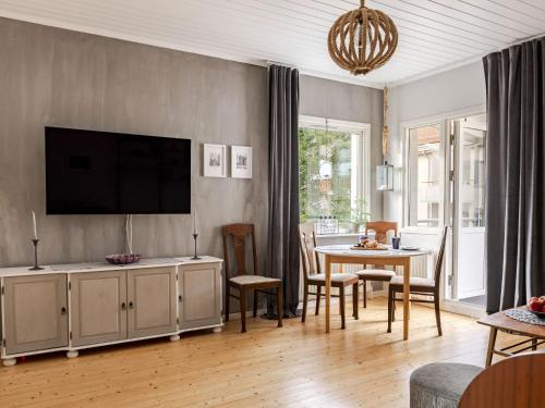 a living room with a television and a table with chairs at Apartment Alegränd by Interhome in Falkenberg