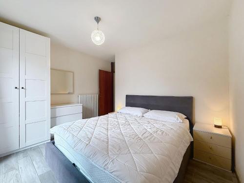 a bedroom with a white bed and a white cabinet at Apartment Marmolada-13 by Interhome in Alba di Canazei