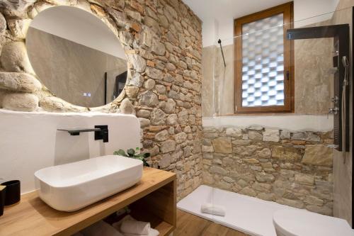 a bathroom with a stone wall and a sink and a mirror at Bellavista Cottage in Barberino di Mugello