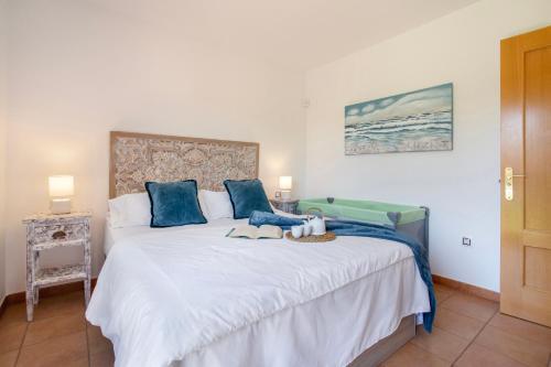 a bedroom with a large white bed with blue pillows at Encantadora Casa Tara in Lajares