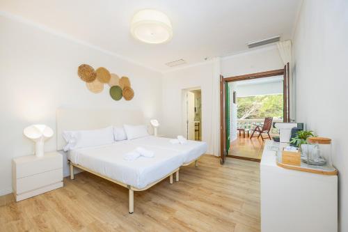 a white bedroom with a large bed and a table at Hostal Boutique Canyamel in Canyamel