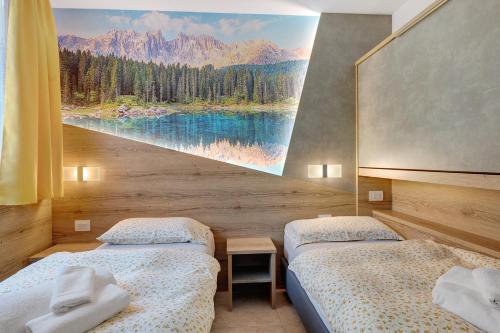 two beds in a room with a painting on the wall at Night and day 8 in Predazzo