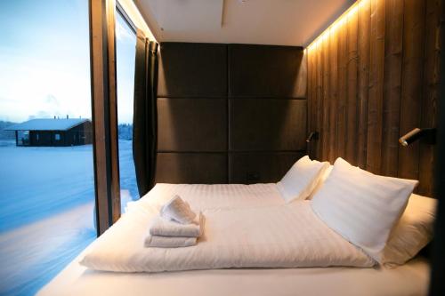 a bedroom with a white bed with towels on it at Sonka Resort Mirror House with Lake View in Rovaniemi