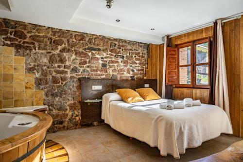 a bedroom with a bed and a stone wall at Aguas del Sella - jacuzzi in Precendi