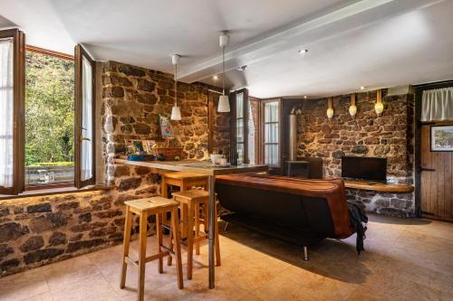 a bar with a piano in a room with stone walls at Aguas del Sella - jacuzzi in Precendi