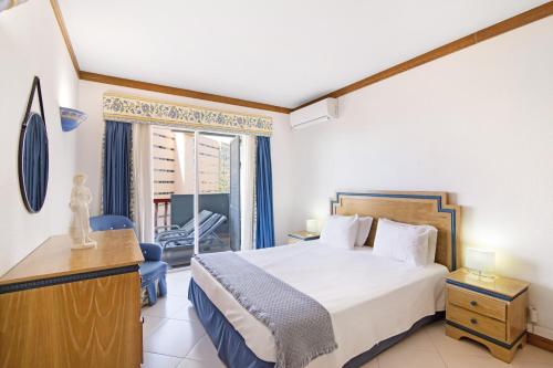 a bedroom with a bed and a desk and a window at T2 com piscina centro Vilamoura in Vilamoura