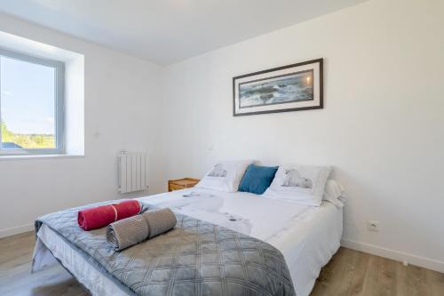 a white bedroom with a large bed and a window at Maison de vacances Chez André in Meslan