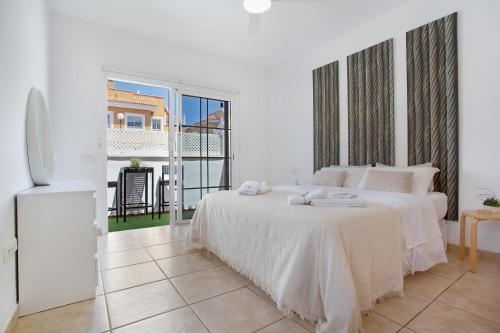 a white bedroom with a bed and a balcony at Apartamento 104 in Caleta De Fuste