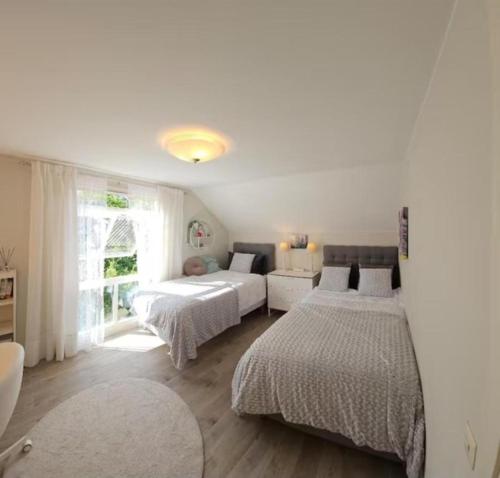 a white bedroom with two beds and a window at Dream house with garden in Kalmar
