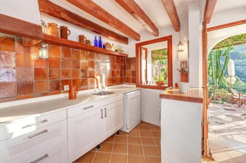a kitchen with white cabinets and a sink at Can Sans in Banyalbufar