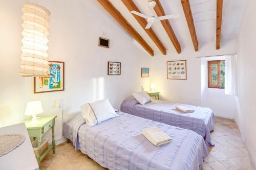two beds in a room with white walls and wooden ceilings at Can Sans in Banyalbufar