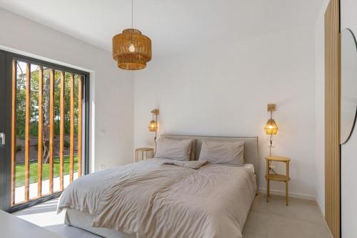 a white bedroom with a bed and a large window at Villa Luma with private Pool in Lazise